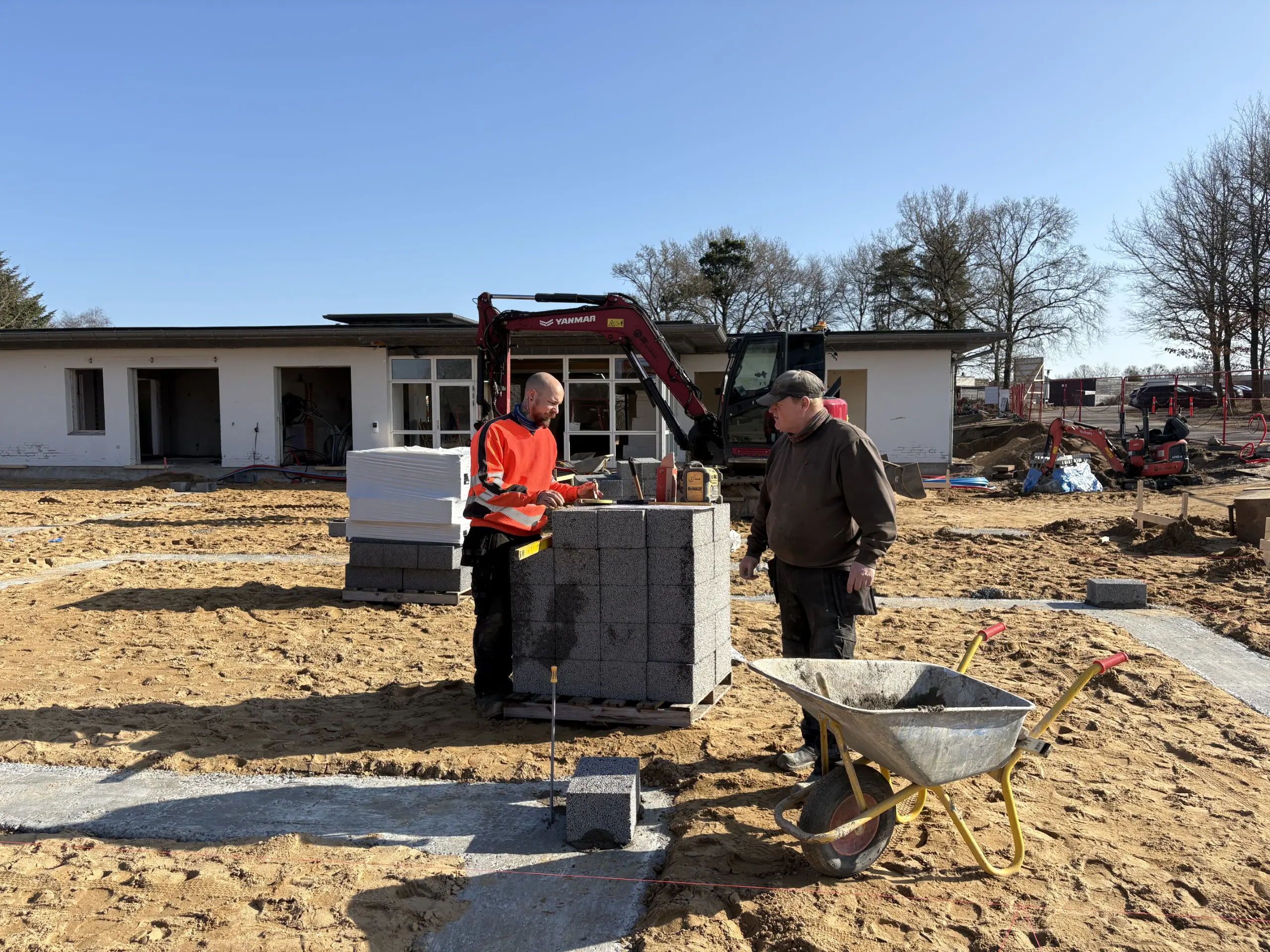 Murere udfører fundamentarbejde og opmuring af sokkel med betonblokke på en byggeplads i Østjylland.