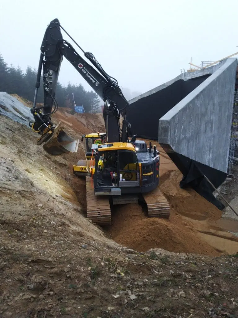Gravemaskine fra Ole Sommer A/S udfører jordarbejde og opfyldning ved en ny betonbro i Hylke.