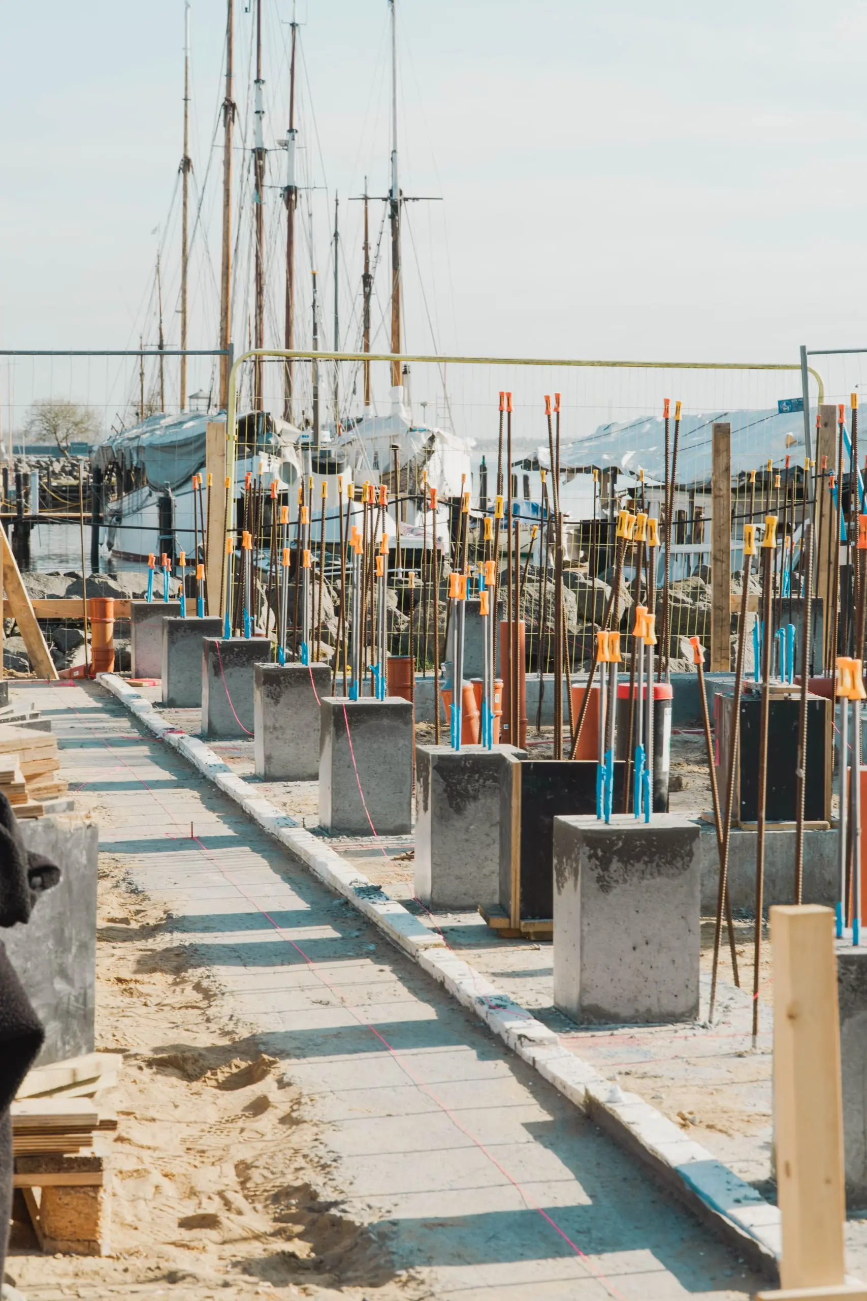 Betonarbejde med støbte fundamenter og armeringsjern med orange sikkerhedshætter på byggeplads i Østjylland.