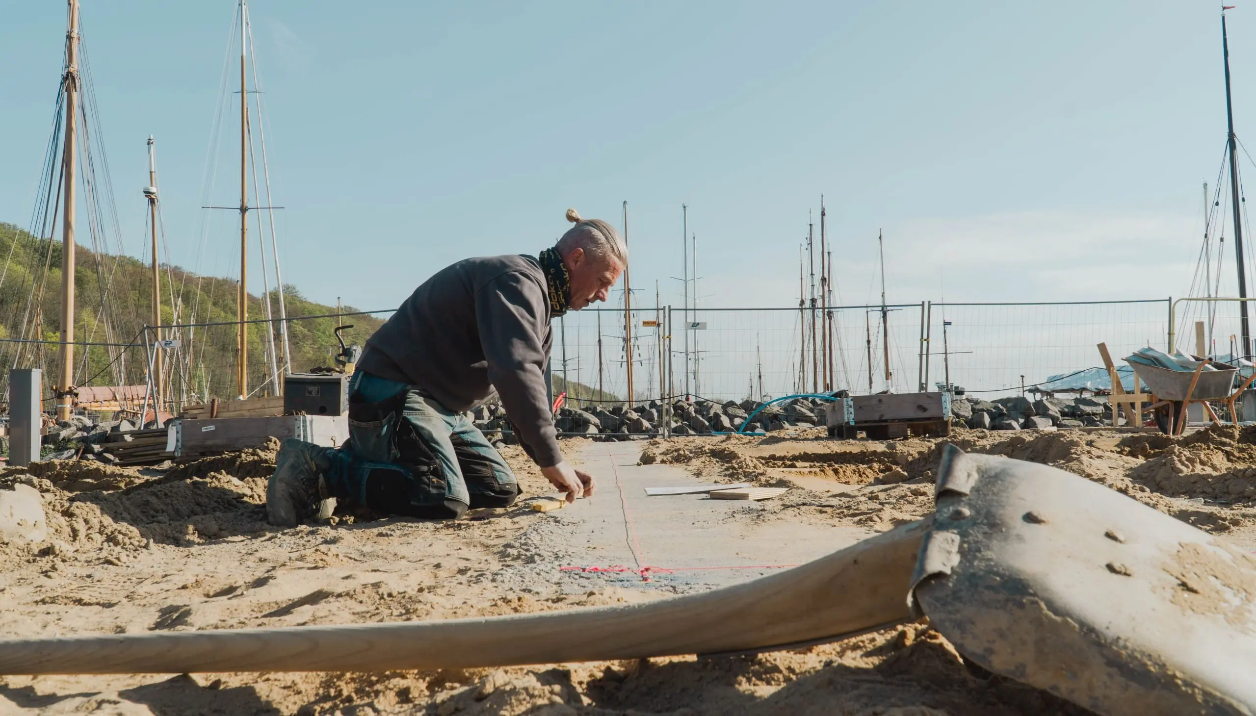 Brolægger udfører præcis afsætning til belægningsarbejde på en havneplads i Østjylland.