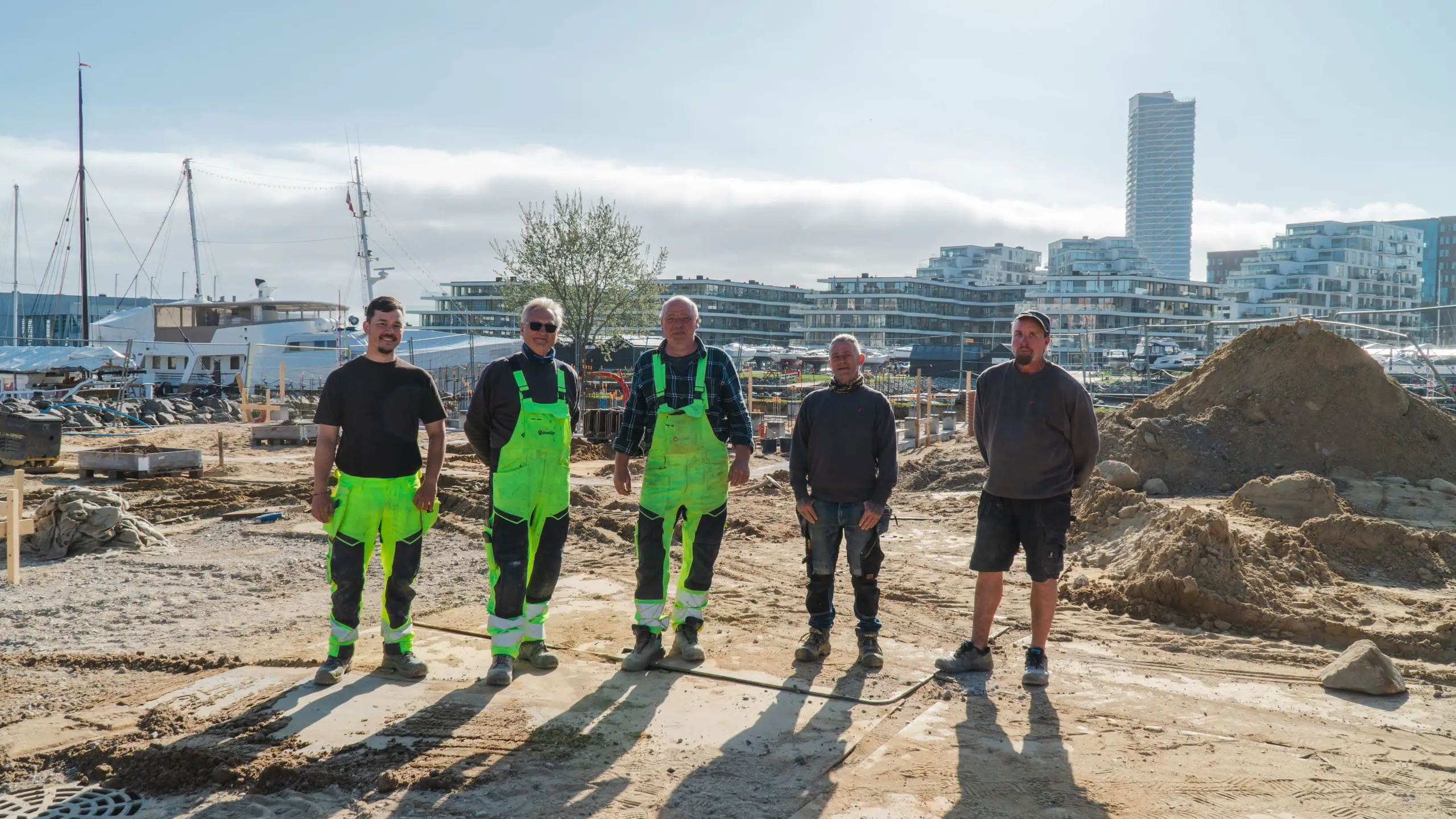 Fem entreprenører fra Ole Sommer A/S ved et anlægsprojekt i Aarhus Ø. Fokus på jordarbejde og professionelt byggeri.