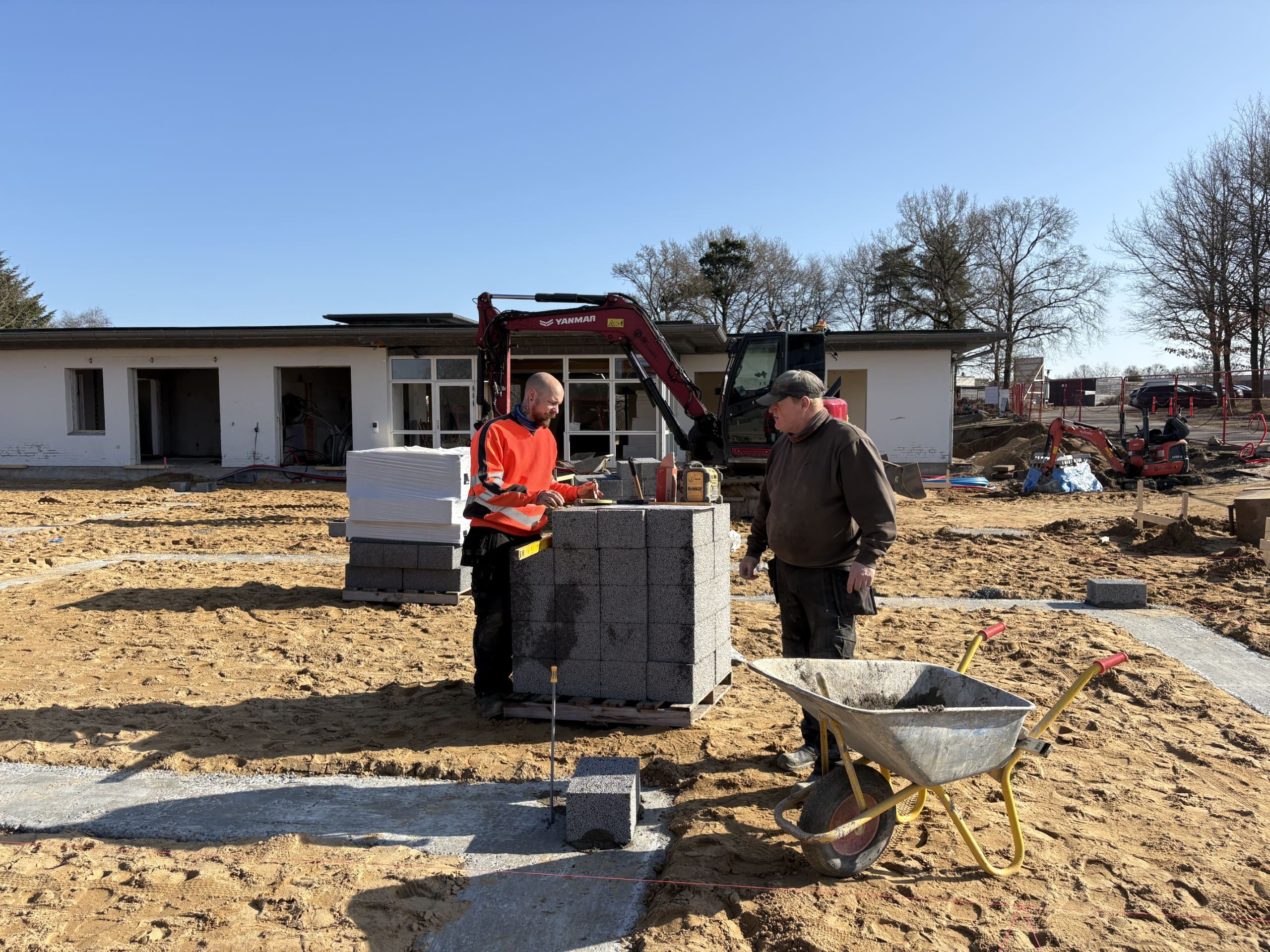 Murere udfører fundamentarbejde og opmuring af sokkel med betonblokke på en byggeplads i Østjylland.