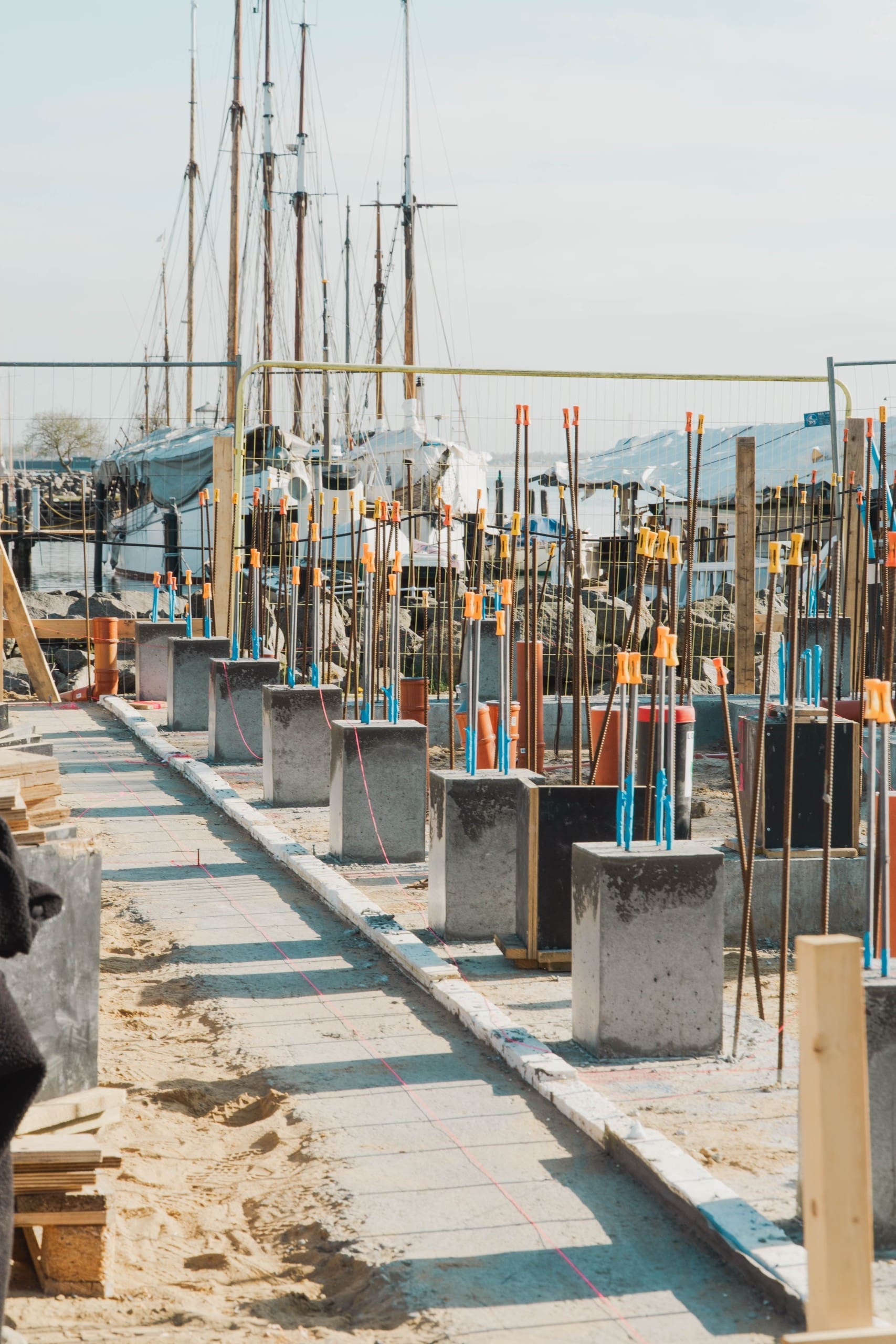 Betonarbejde med støbte fundamenter og armeringsjern med orange sikkerhedshætter på byggeplads i Østjylland.