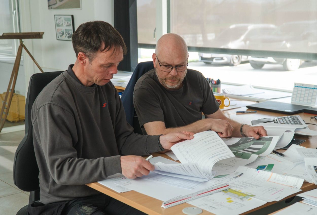 To medarbejdere hos Ole Sommer A/S gennemgår tekniske tegninger og dokumentation for et projekt i Østjylland.