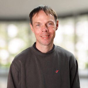 Portrætfoto af Morten Sommer iført en mørk sweatshirt og smilende mod kameraet